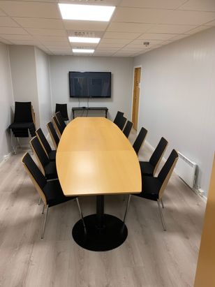 Lite møterom med langbord og skjerm
